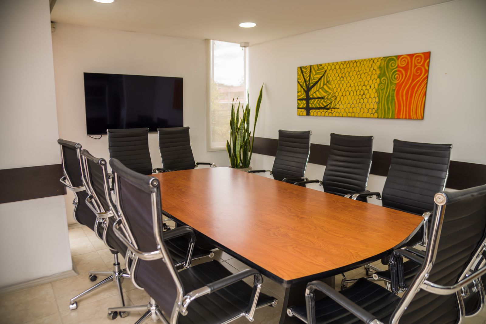 Sala M con mesa ovalada de madera, sillas ejecutivas y pantalla