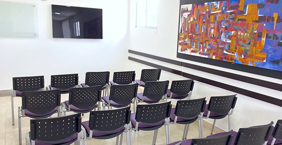 Auditorio con filas de sillas frente a una pantalla